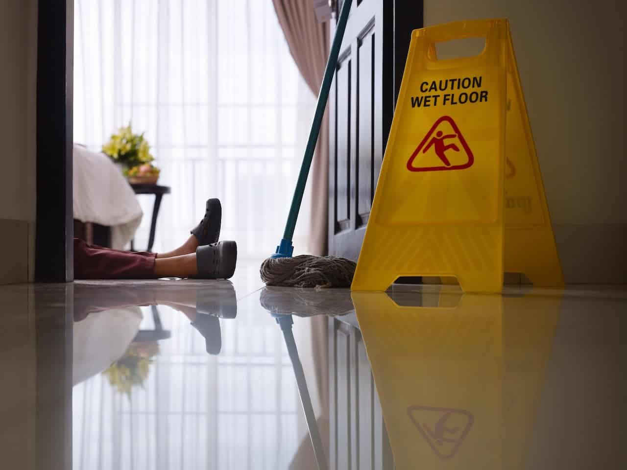 maid slipped and fell on wet floor. lying on ground next to wet floor sign
