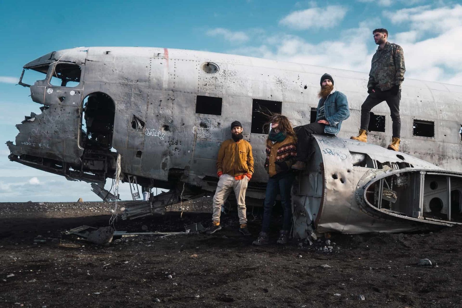 Group of young survivors, in need of an airplane accident attorney, standing on crashed aircraft in desert